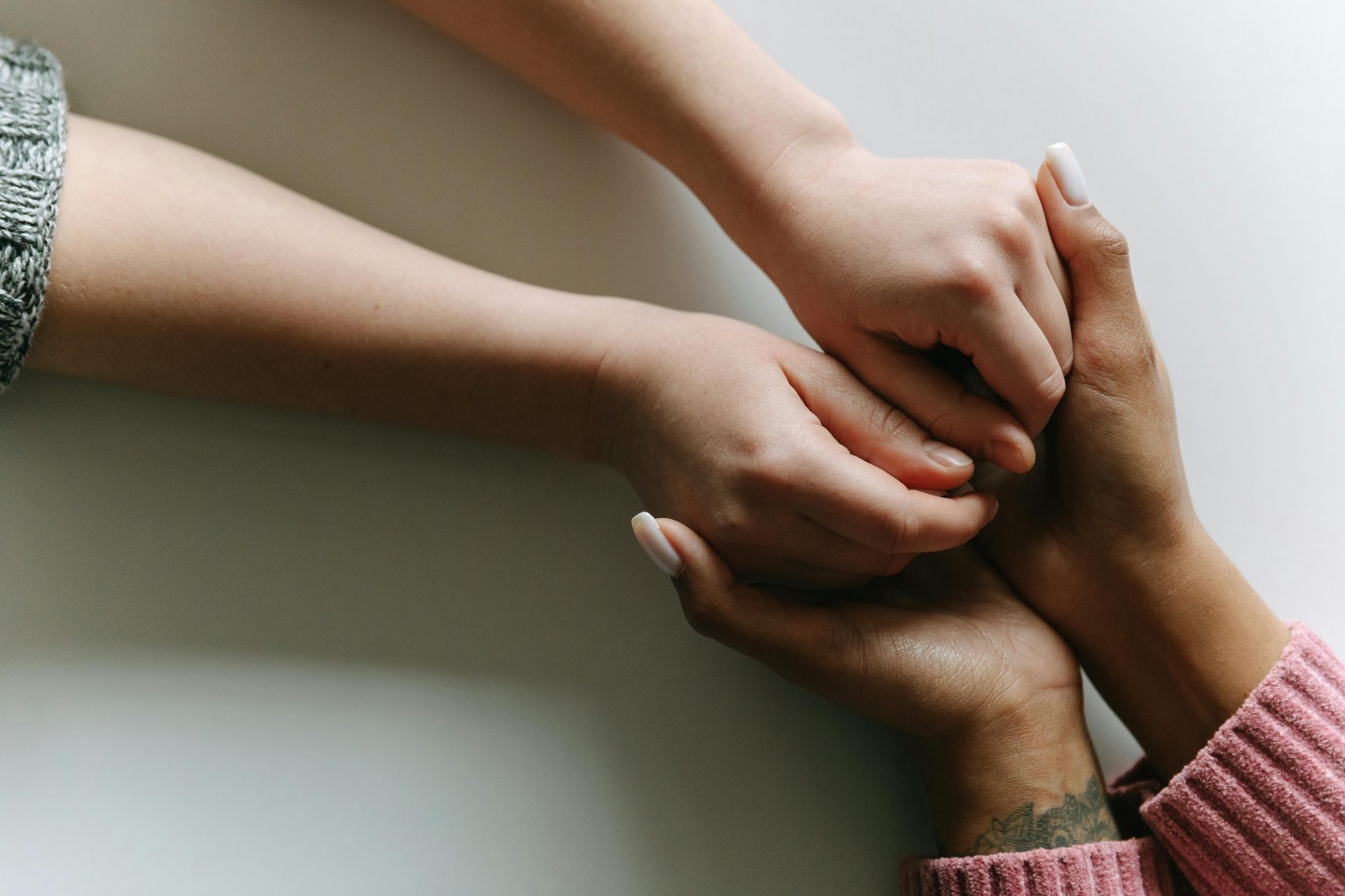 Gros plan sur des mains de formes diverses se tenant, symbolisant l'attention, le soutien et l'amitié.