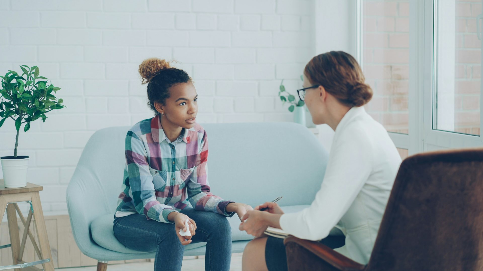 Une thérapeute parle à une jeune femme allongée sur un canapé.